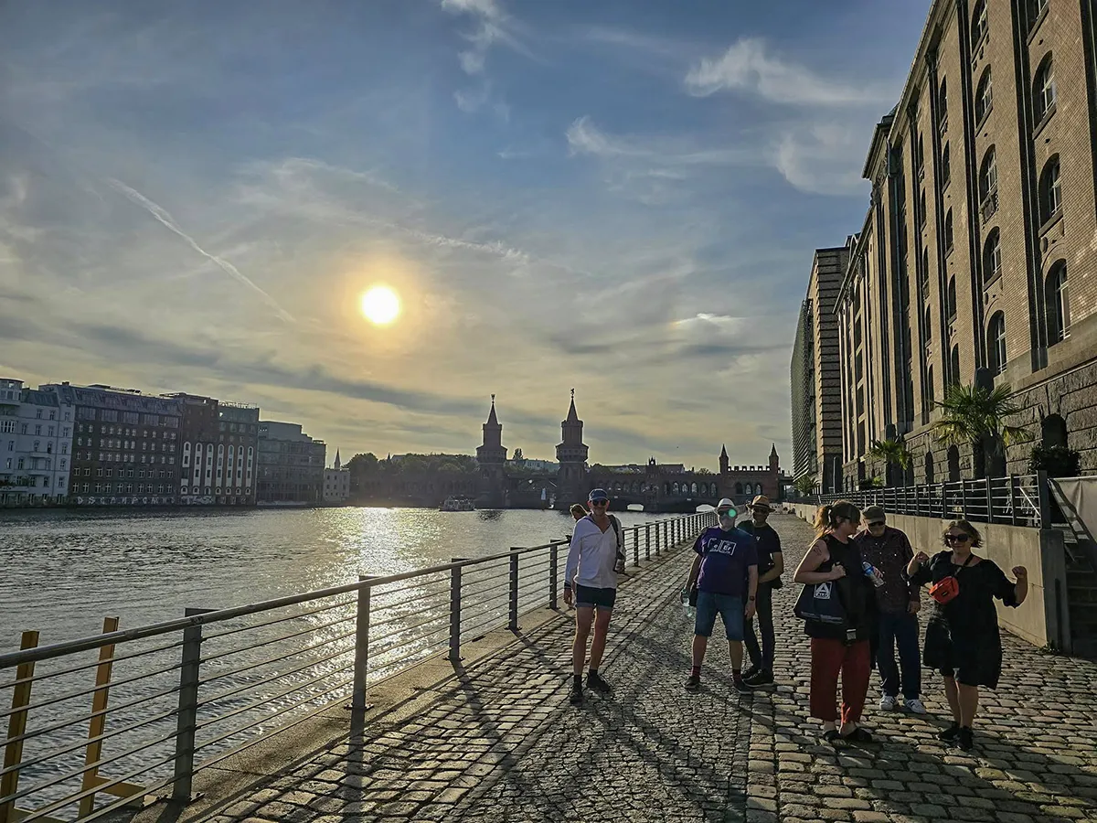 Eine Gruppe spaziert am Spreeufer bei Sonnenuntergang