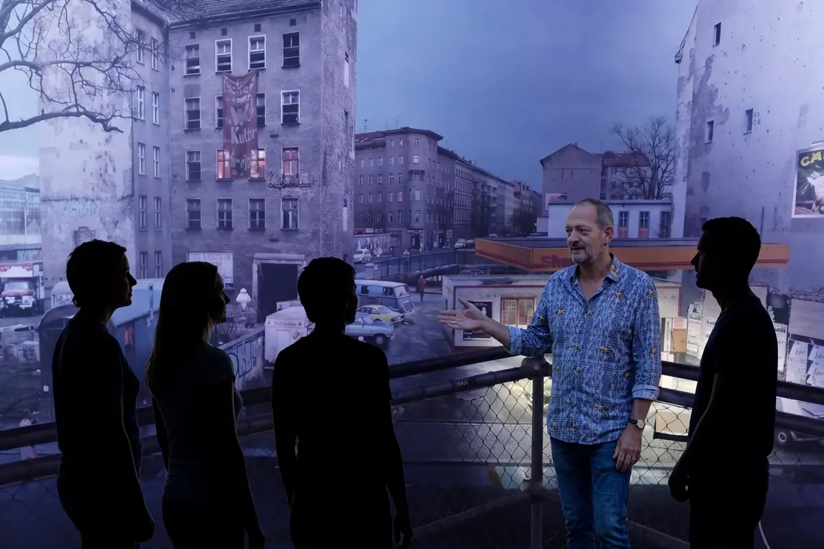 Kontext guide, Klaus, inside the asisi Panorama Berlin, 'Die Mauer' with a group of tour guests