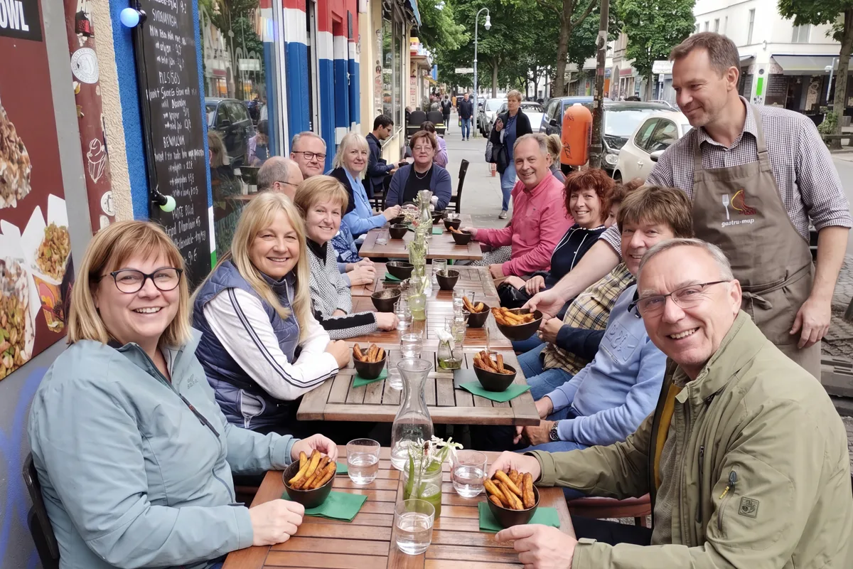 Large group of tour guests with a portion of fried plantain just served on the Wrangelstraße, Kreuzberg